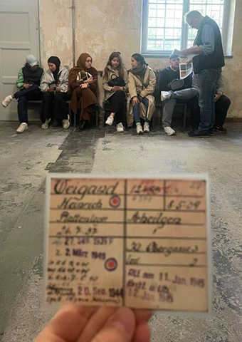 Frauen und Männer sitzen auf Stühlen vor einer Wand.  (Quelle: Taner Yüksel) Frauen und Männer sitzen auf Stühlen vor einer Wand.